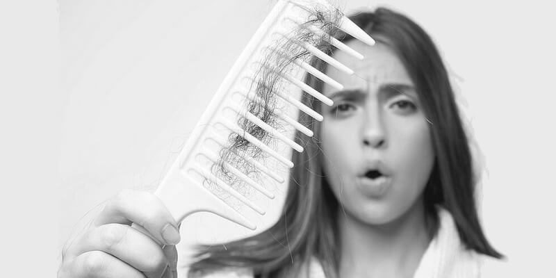 Femme montrant la chute de ses cheveux avec un peigne