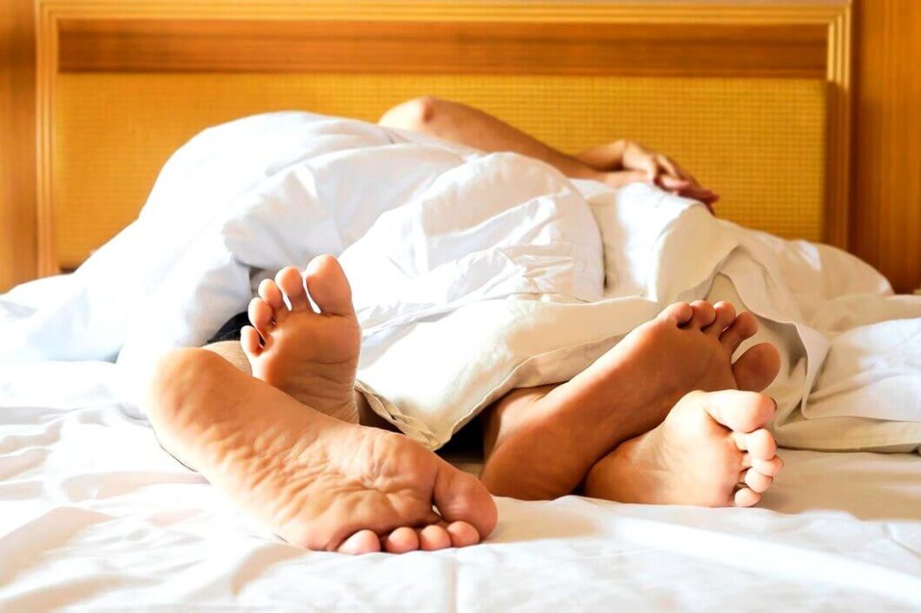 Couple sur un lit blanc dans une chambre d'hôtel